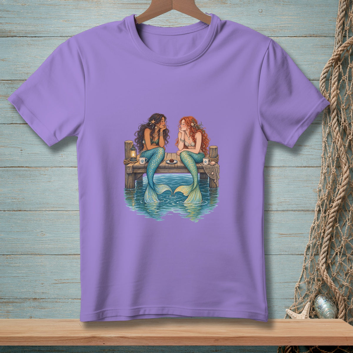 Two mermaids sit on a dock talking, with tails in the water.