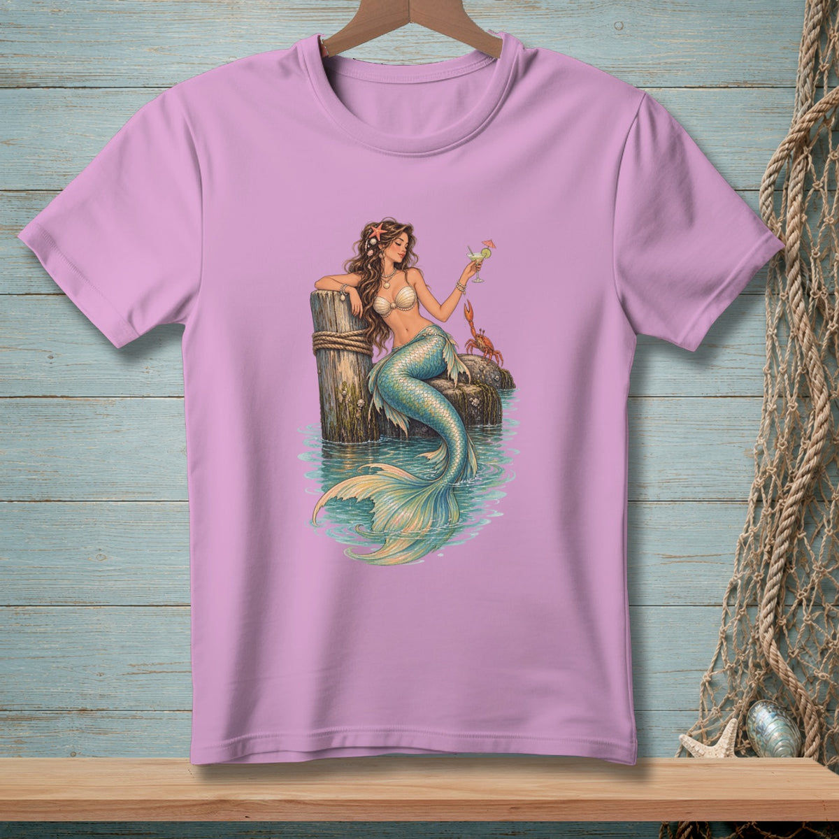 Mermaid with a drink and crab sits on a pier with turquoise water.