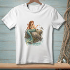 White t-shirt with a mermaid sitting on rocks with a seagull, holding a glass of wine.
