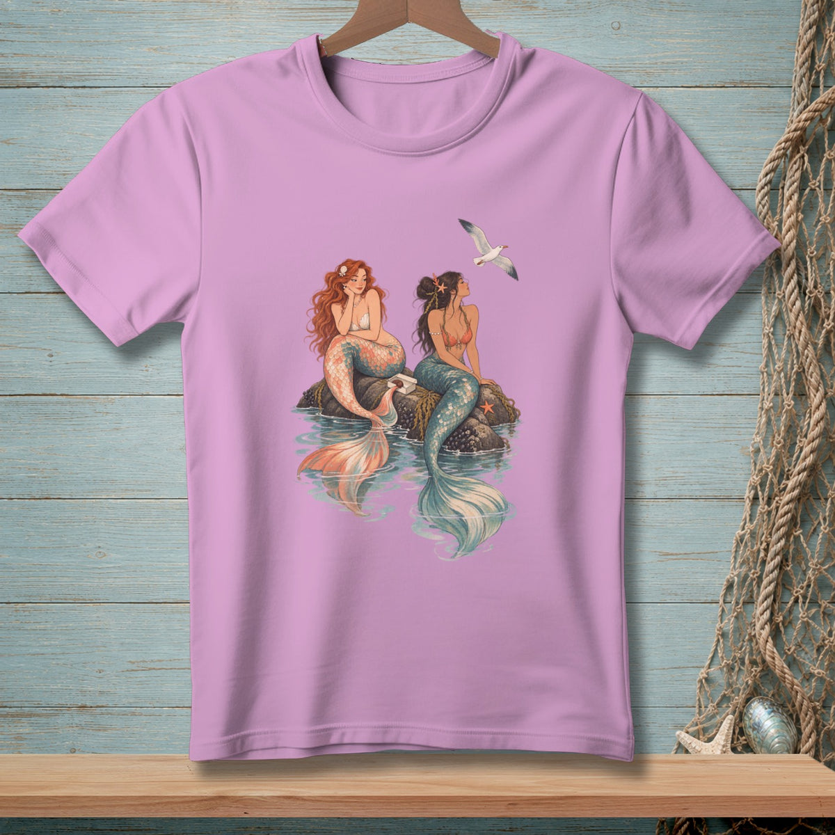 Pink t-shirt with two mermaids and a seagull illustration.