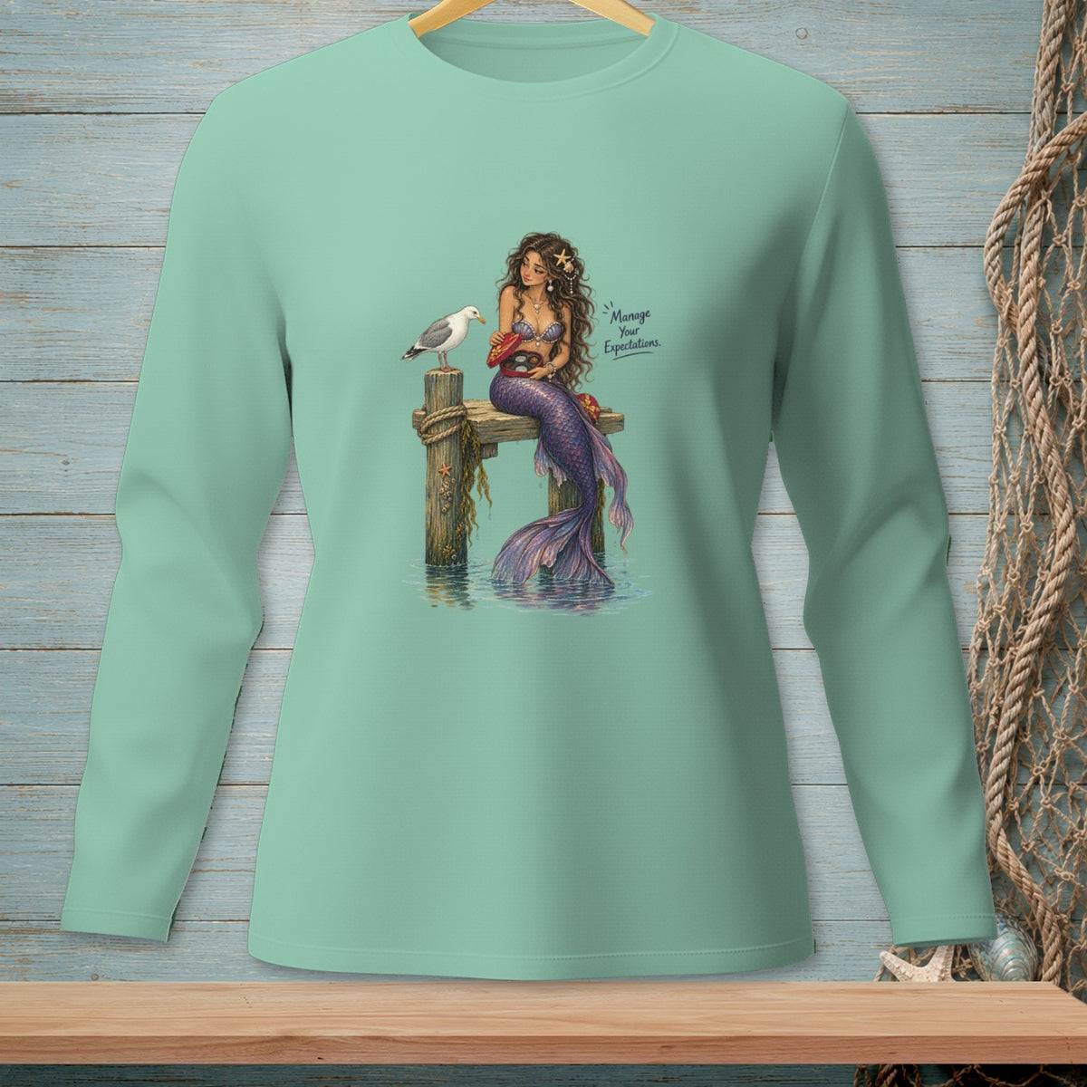 Mermaid sitting on a pier with a seagull and crab, text says "Manage Your Expectations."