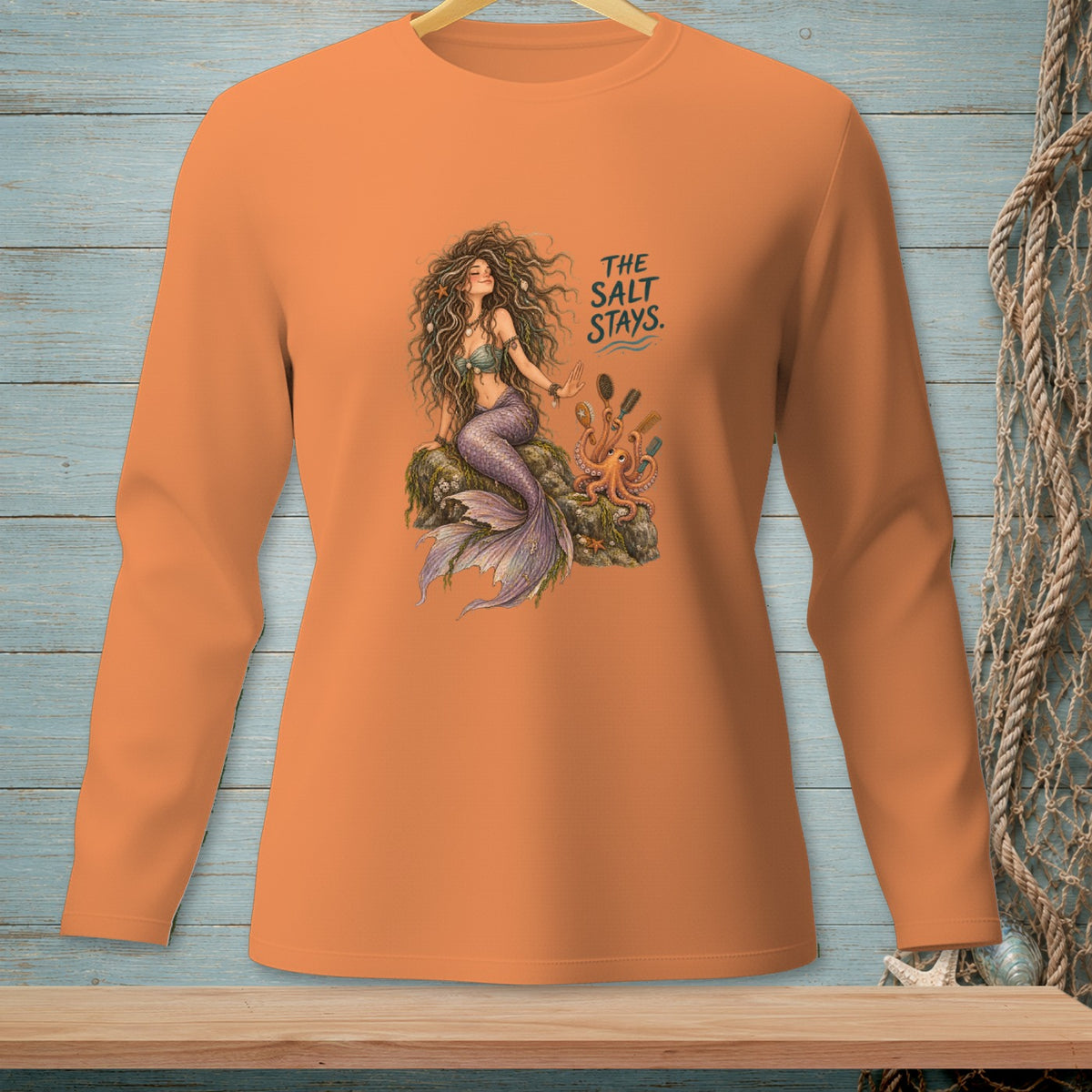 Orange long-sleeve shirt featuring a mermaid with an octopus and "The Salt Stays" text.