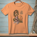 Orange t-shirt with a mermaid and octopus illustration, text reads "THE SALT STAYS."