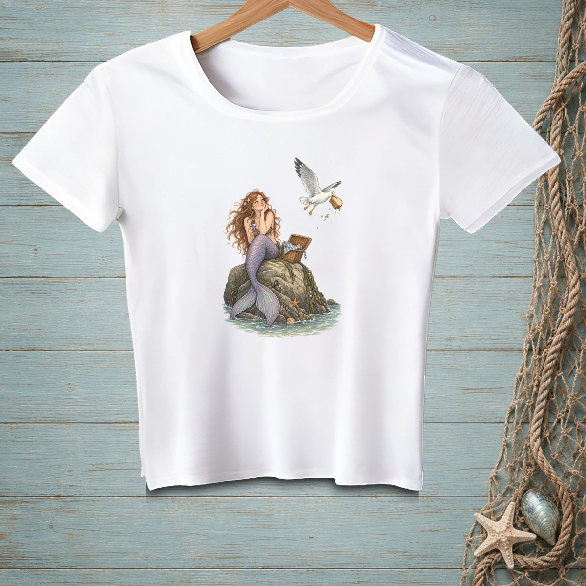 White t-shirt with a graphic of a mermaid and a seagull stealing a sandwich.