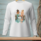 Two mermaids with colorful tails sit on a pier talking over coffee.