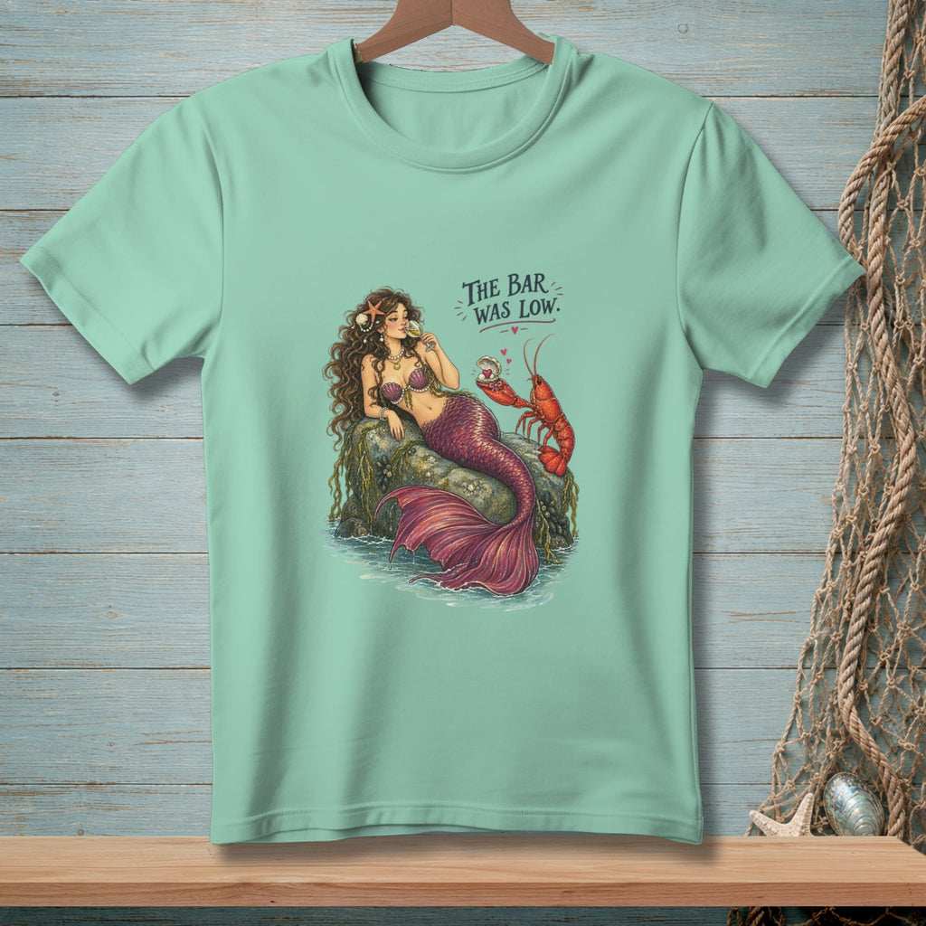 Mermaid and lobster with text "The Bar Was Low" on a light teal t-shirt.