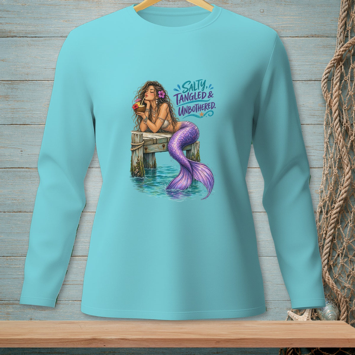 Mermaid with purple tail on a dock drinking from a coconut, with "Salty, Tangled & Unbothered" text.