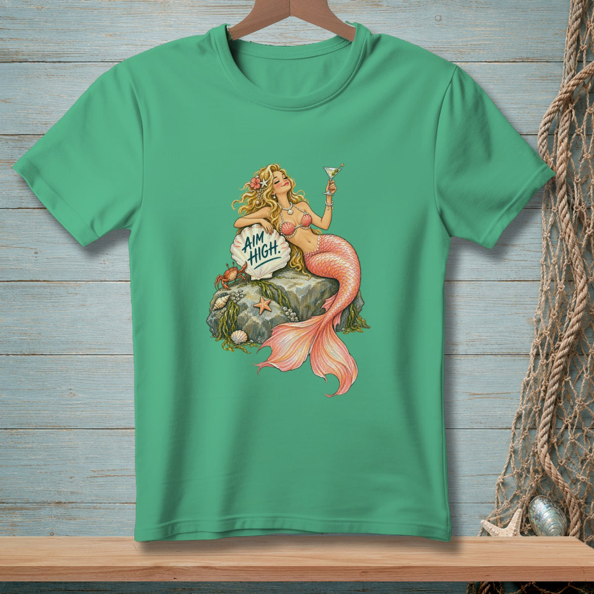 Green t-shirt with a mermaid holding a martini and a shell that reads "AIM HIGH."