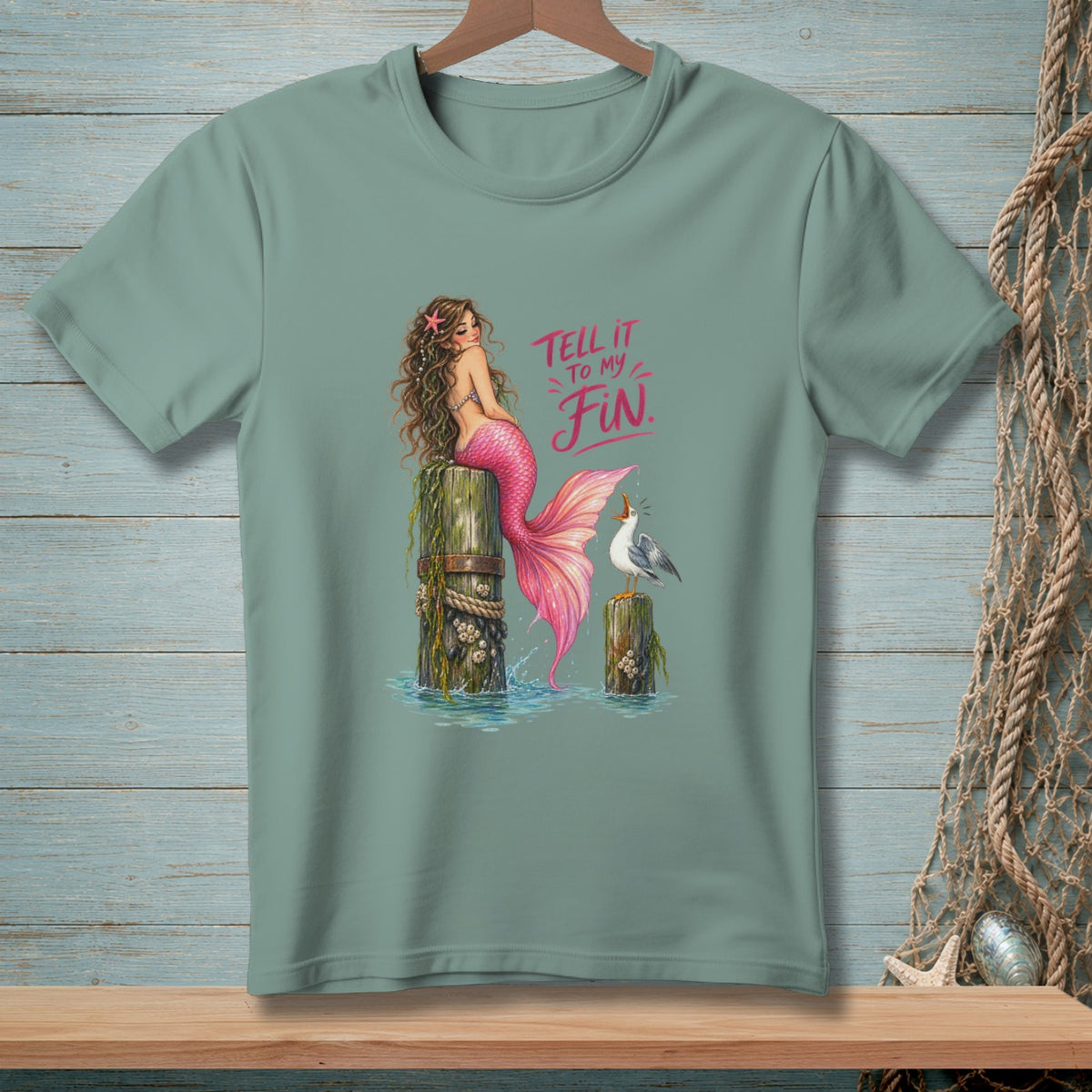 Mermaid with pink tail sits on post with seagull and text "Tell it to my Fin."
