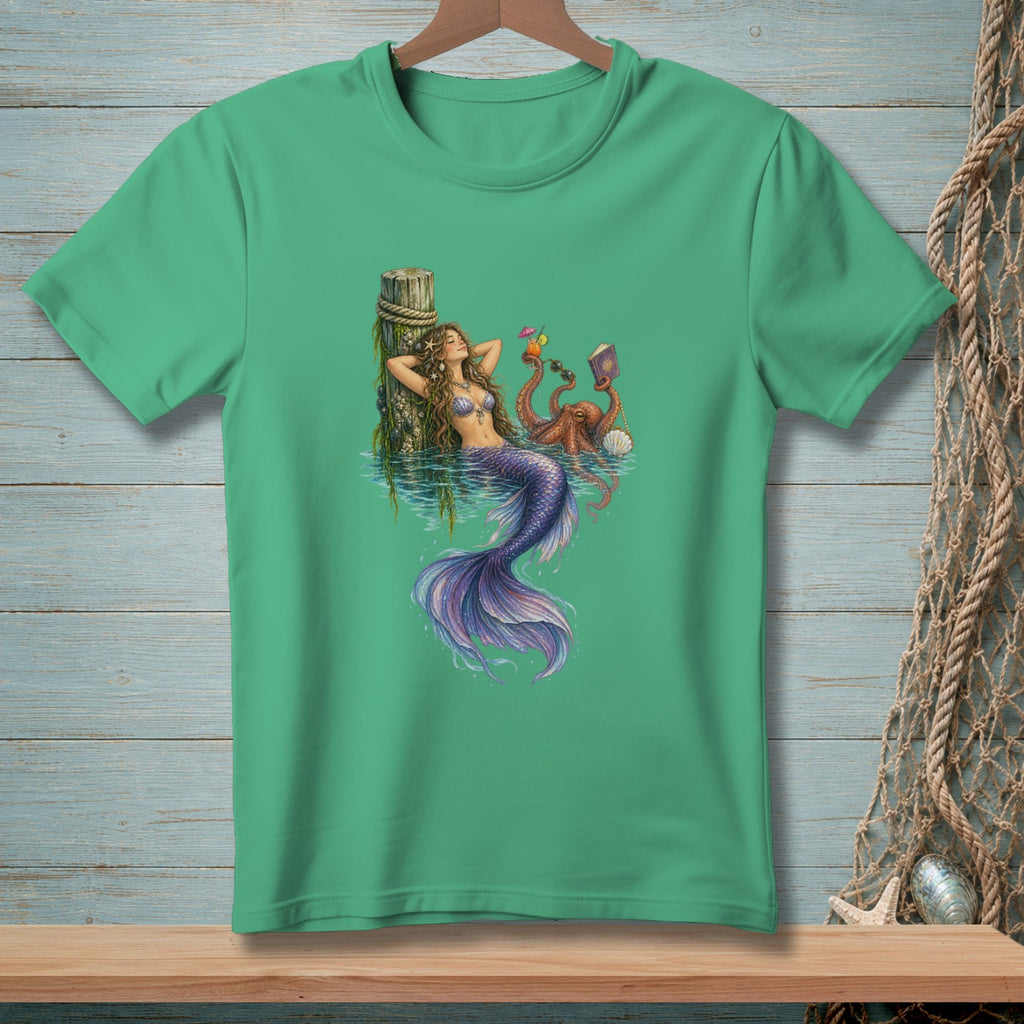 Mermaid relaxes by pier with octopus, holding sunglasses and a book.