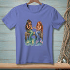 Two mermaids sit on a dock sharing berries.