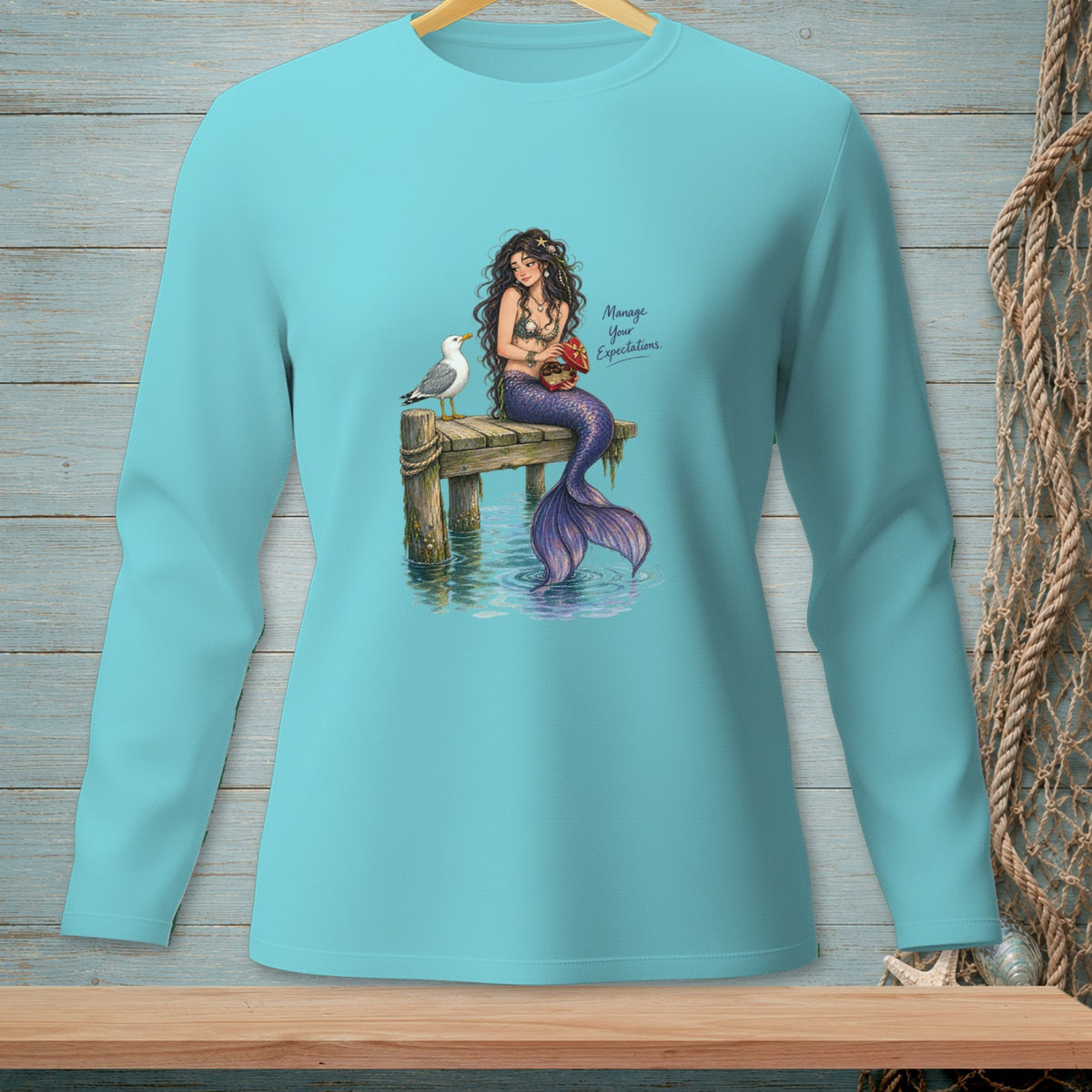 Turquoise shirt with a mermaid, seagull, and text "Manage Your Expectations."