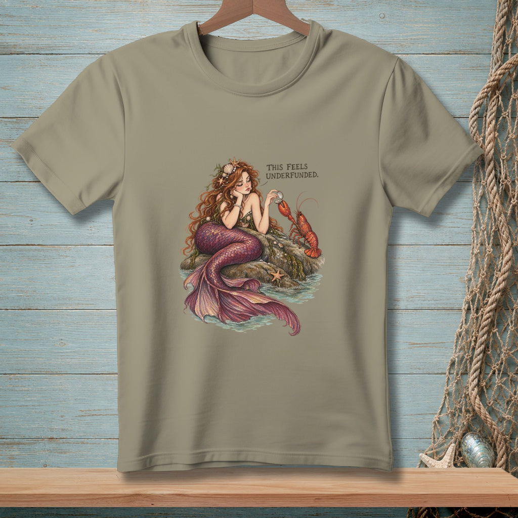 T-shirt graphic: Mermaid resting on rocks with a lobster, text reads "This Feels Underfunded."