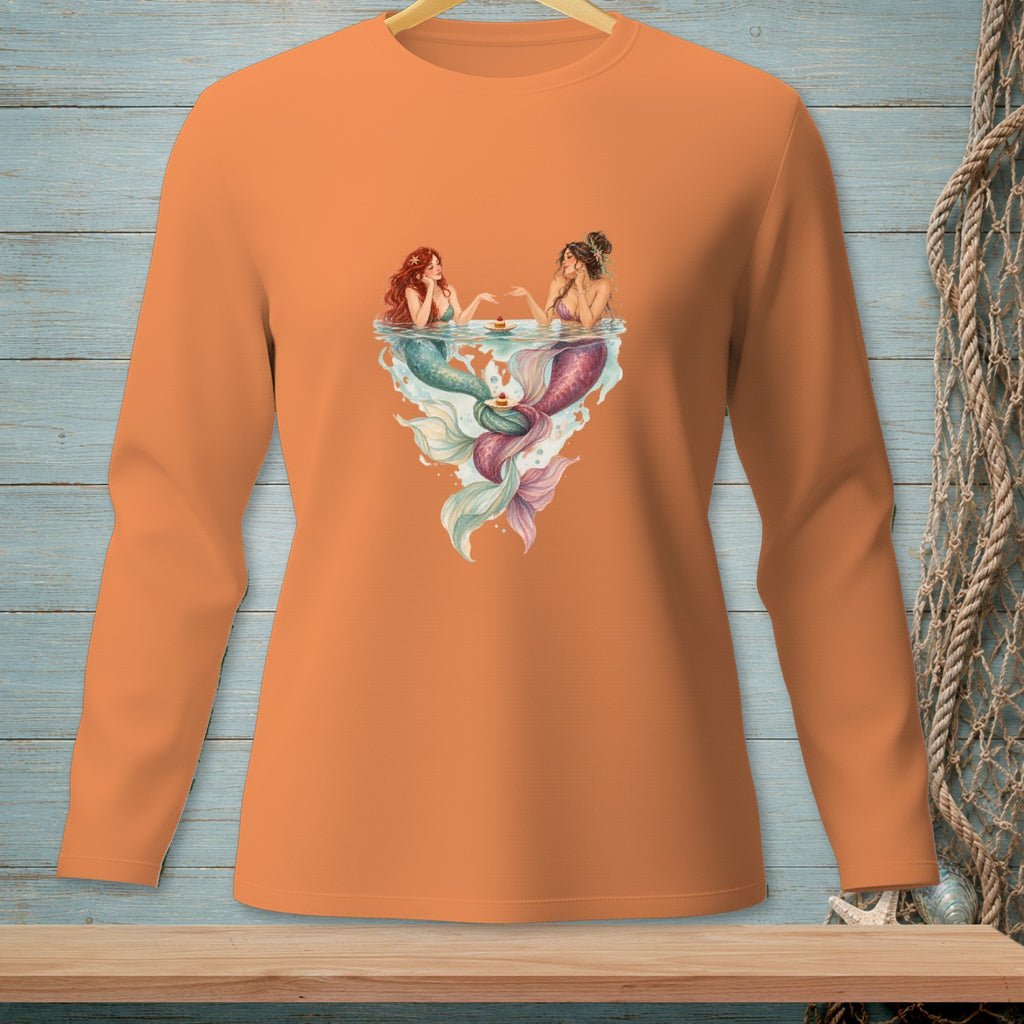 Two mermaids sharing cupcakes in a heart-shaped splash on an orange shirt.