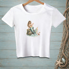 White t-shirt with mermaid and crab graphic, holding a drink on a rock.