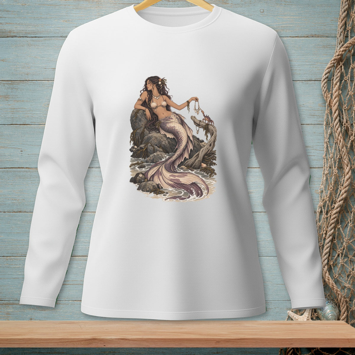 White long-sleeve shirt with a mermaid sitting on rocks by the ocean.