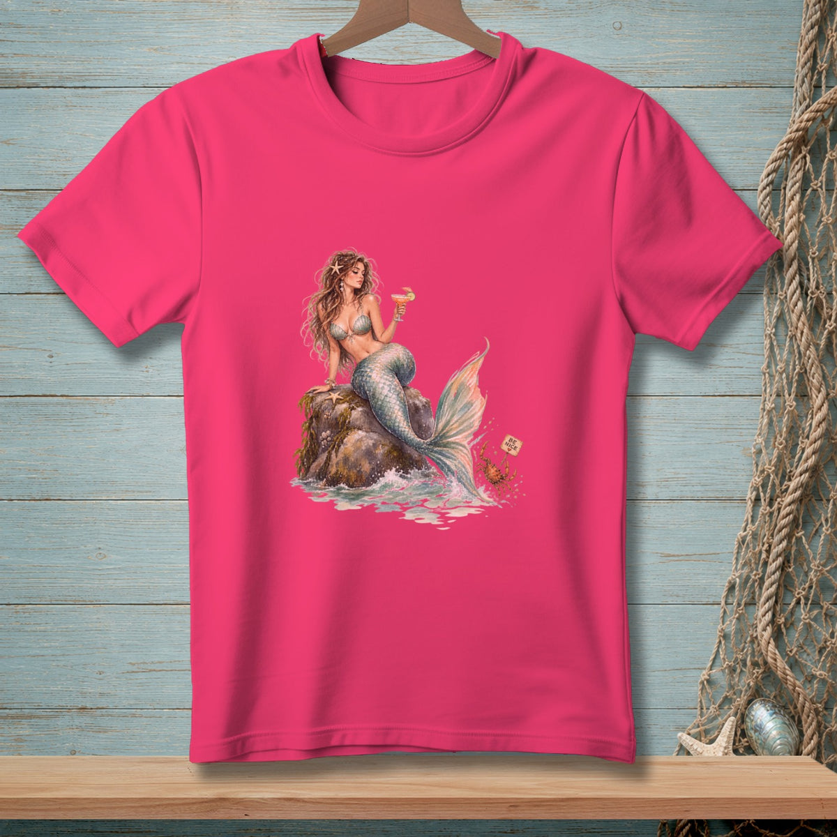 Mermaid on rock with drink, crab with "Be Nice" sign, on pink t-shirt.