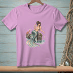 Lilac t-shirt with a watercolor graphic of a mermaid, crab, and seashells on rocks.