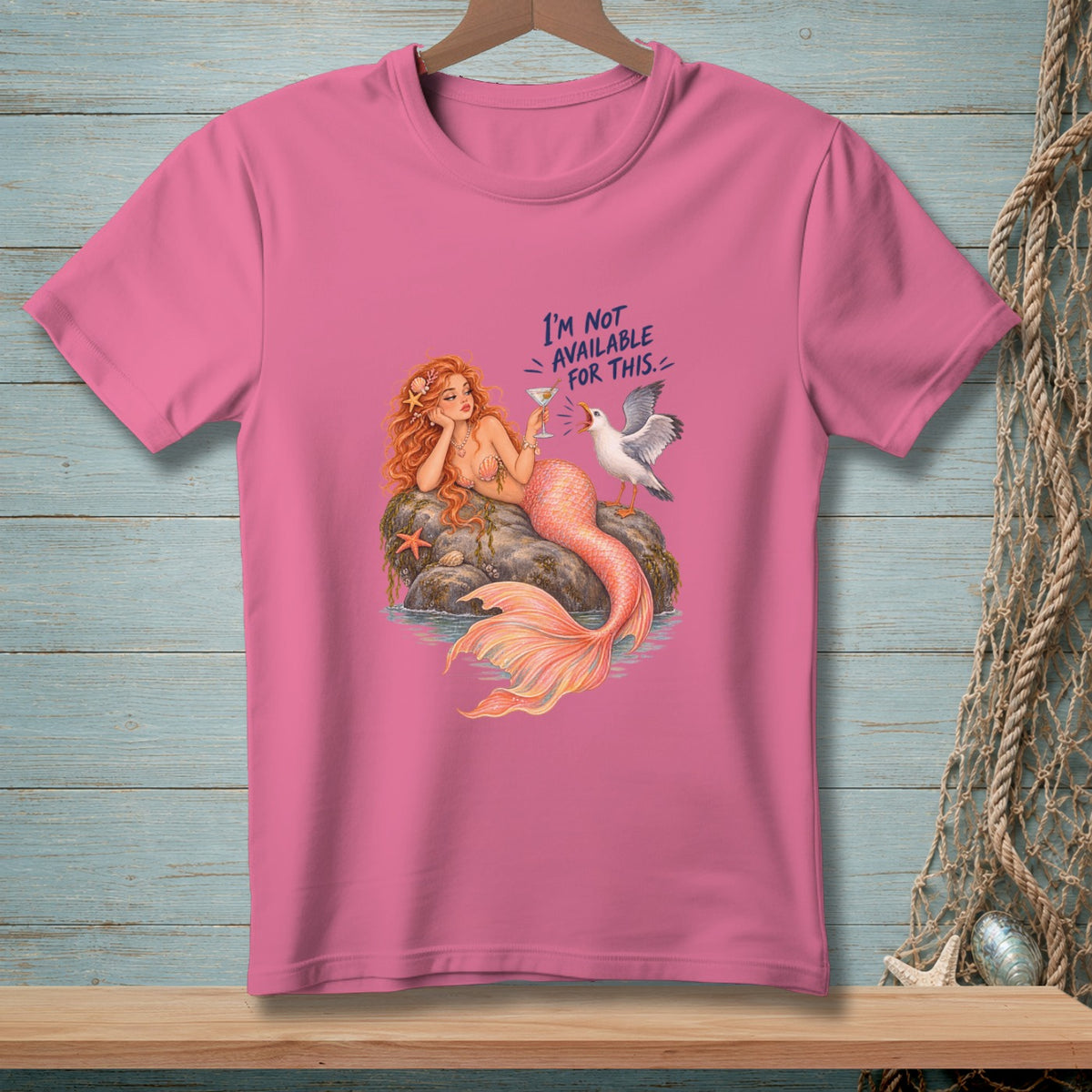 Pink t-shirt with mermaid and seagull graphic reading "I'm not available for this."