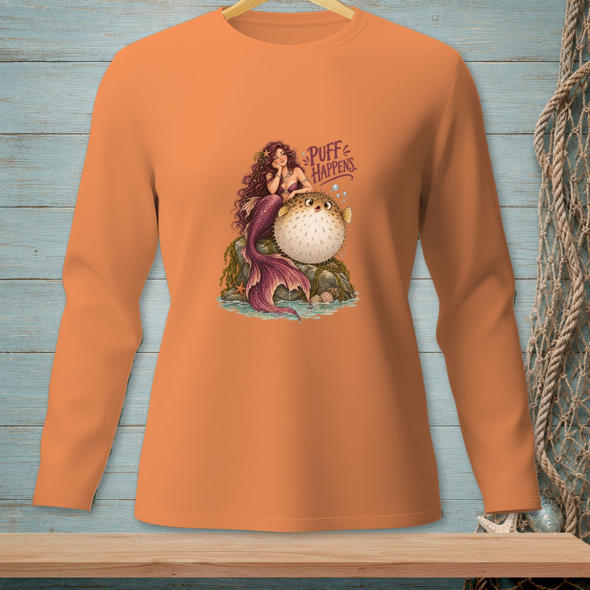 Orange long-sleeve shirt with a mermaid and pufferfish graphic that says "Puff Happens".