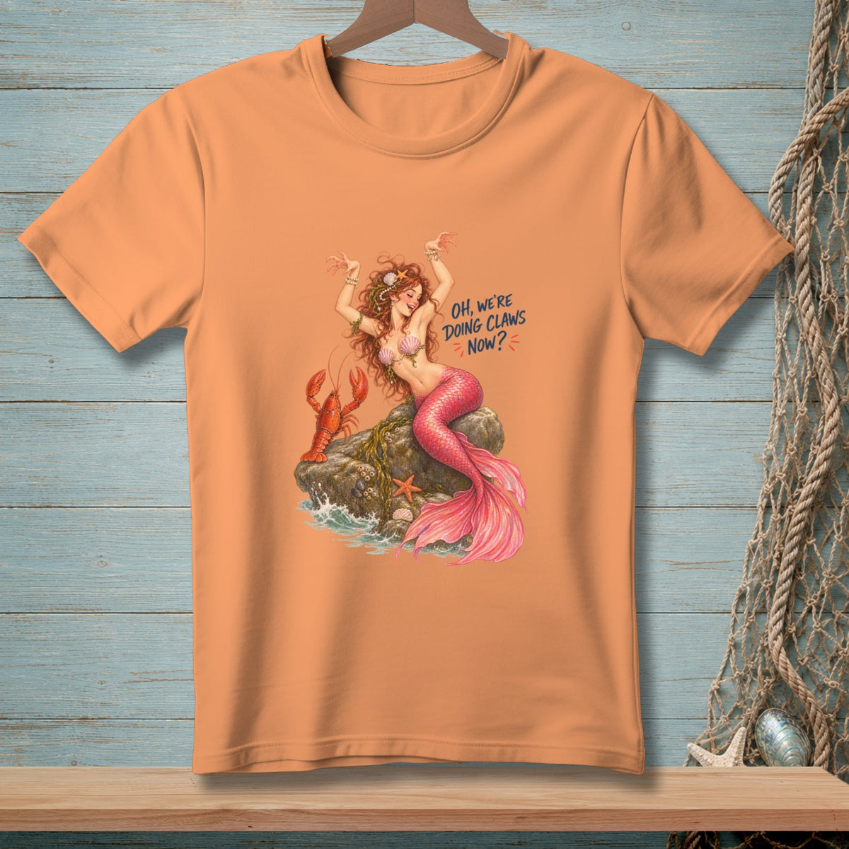 Orange t-shirt with mermaid, lobster, text "Oh, We're Doing Claws Now?"