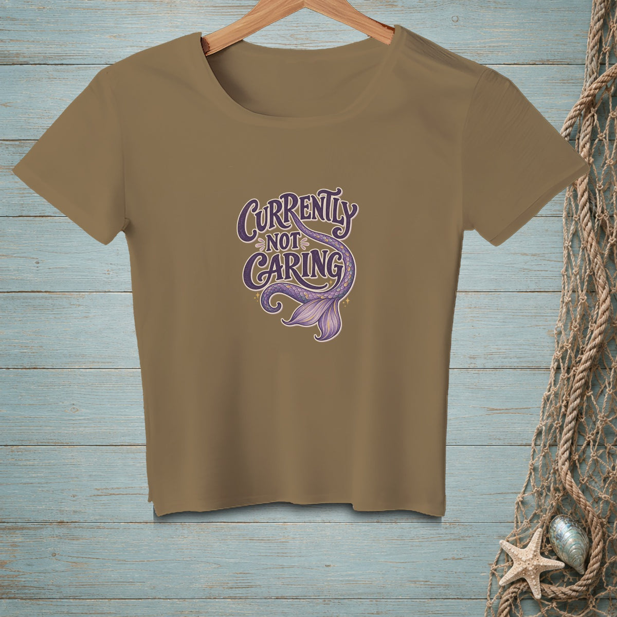 Brown t-shirt with purple text and mermaid tail graphic that says "Currently Not Caring".