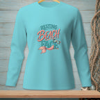 Teal long-sleeve shirt with "Resting Beach Face" text and mermaid tail graphic.