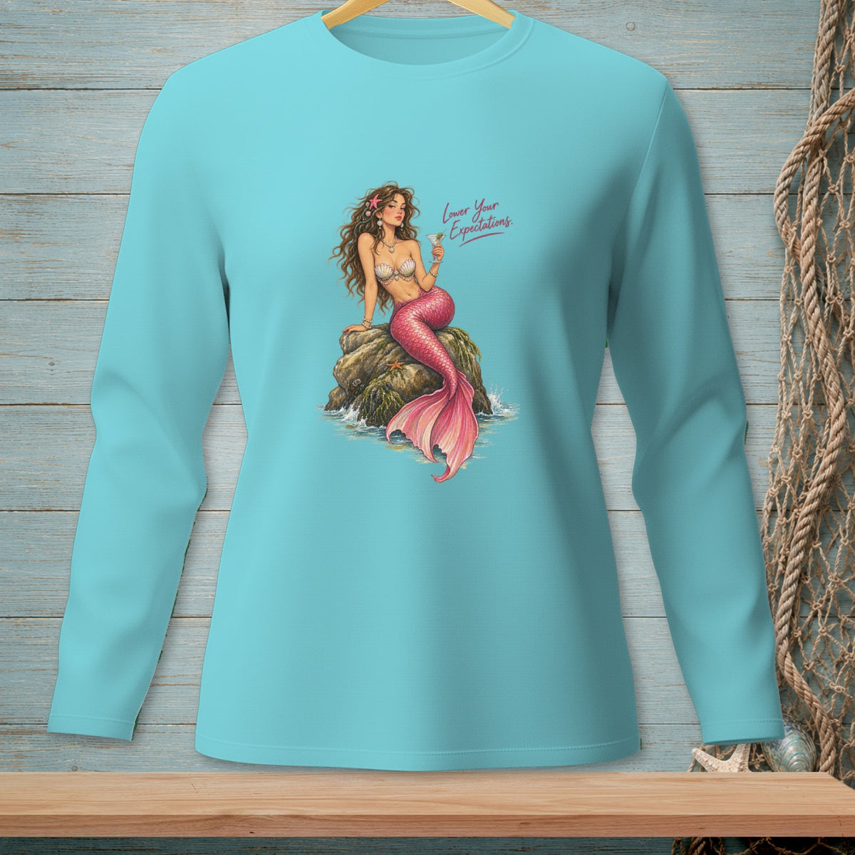 Turquoise long-sleeve shirt with mermaid graphic and text "Lower Your Expectations."