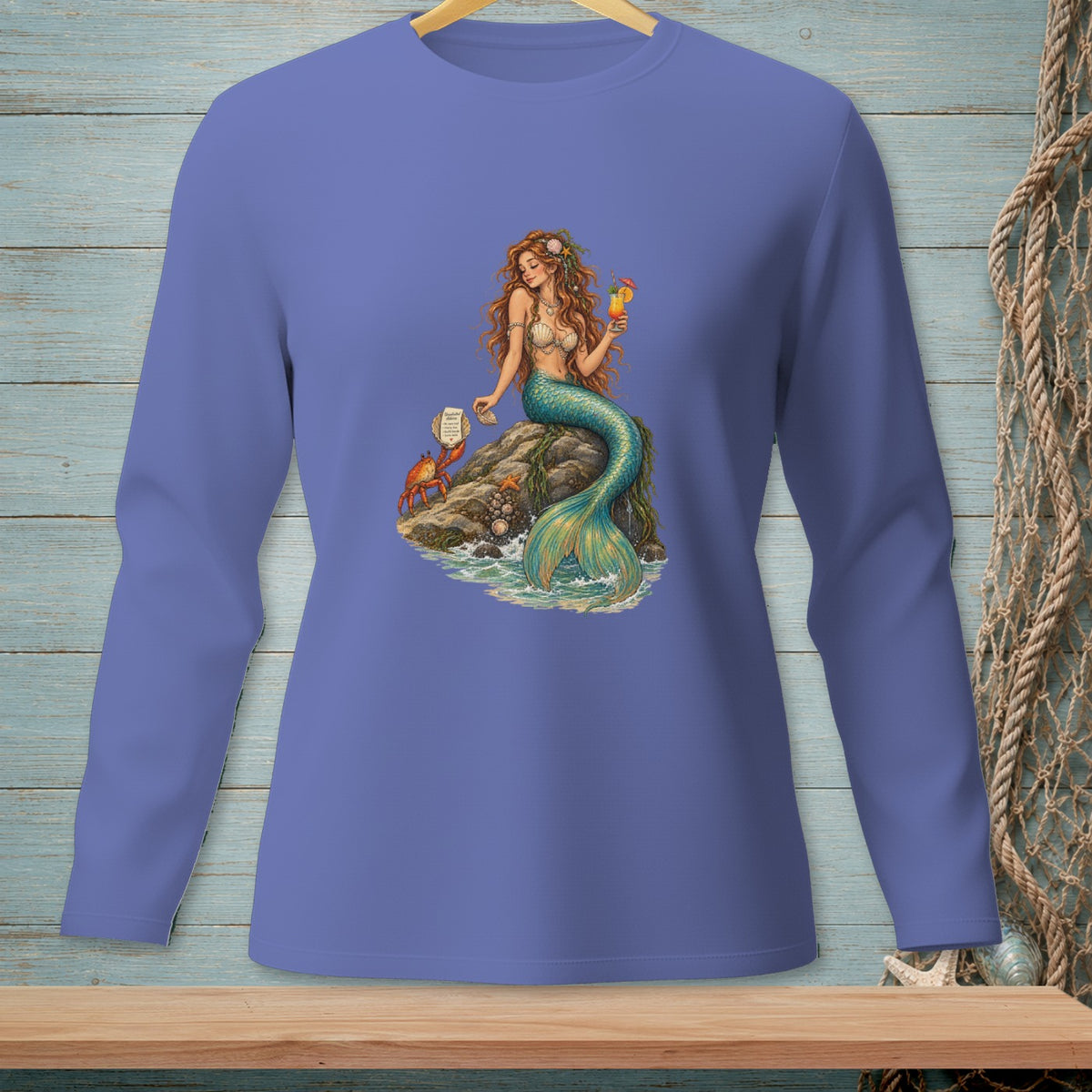 Mermaid sitting on a rock with a drink and a crab nearby, on a blue shirt.