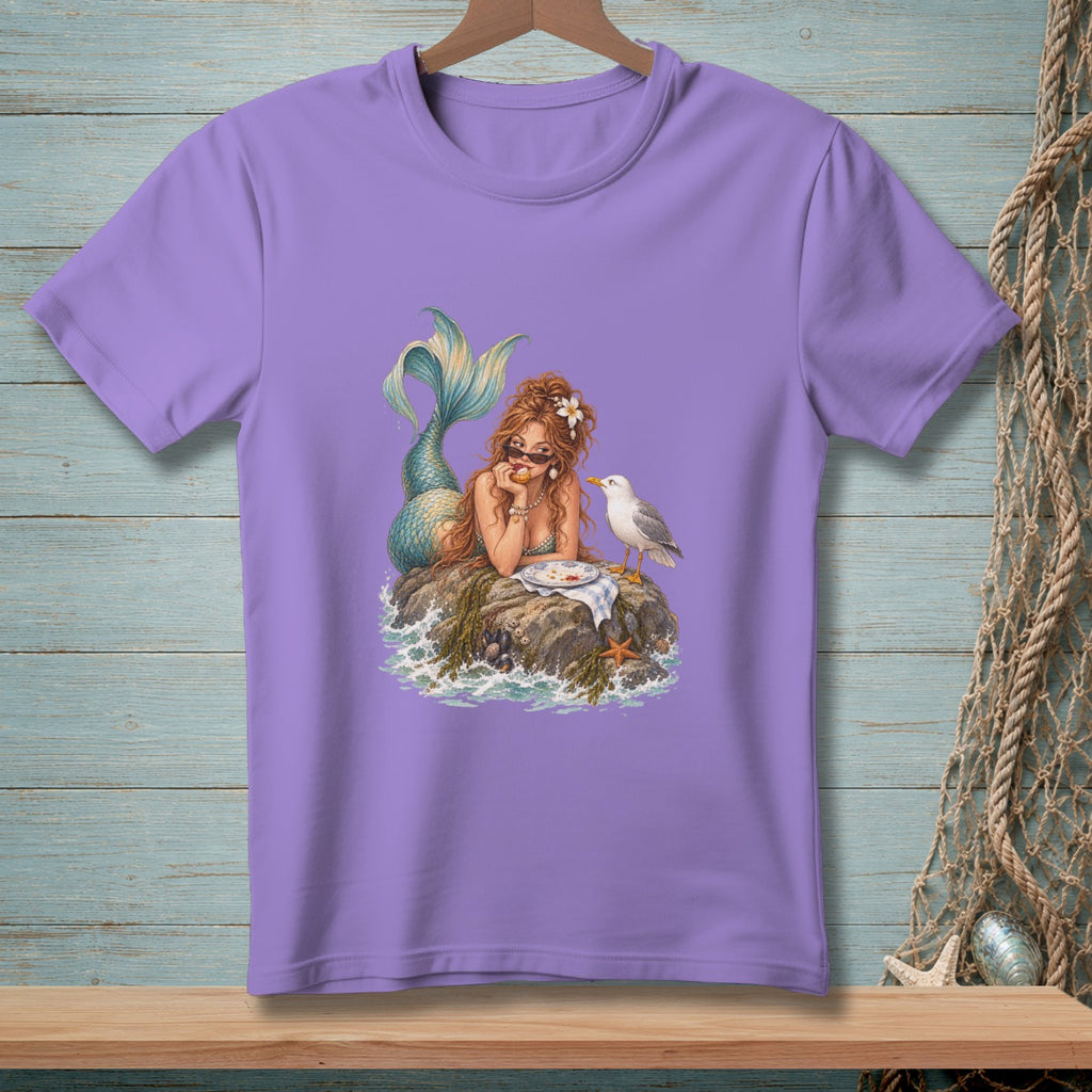 Purple t-shirt featuring a mermaid eating on a rock with a seagull nearby.