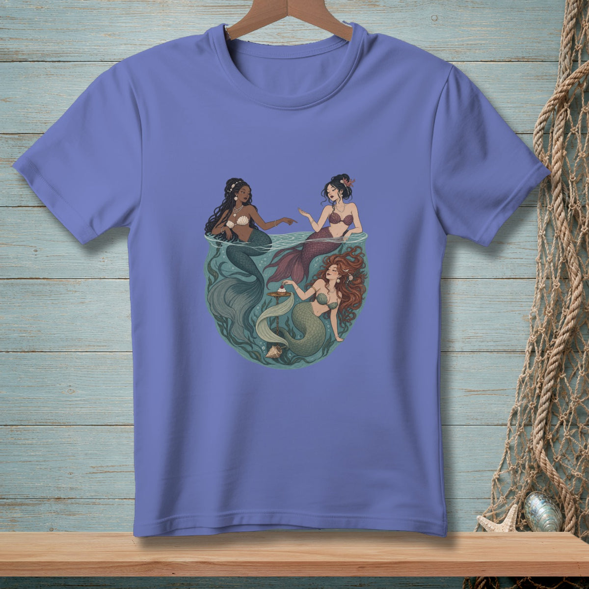 Illustration of three mermaids in a circular design on a purple t-shirt.