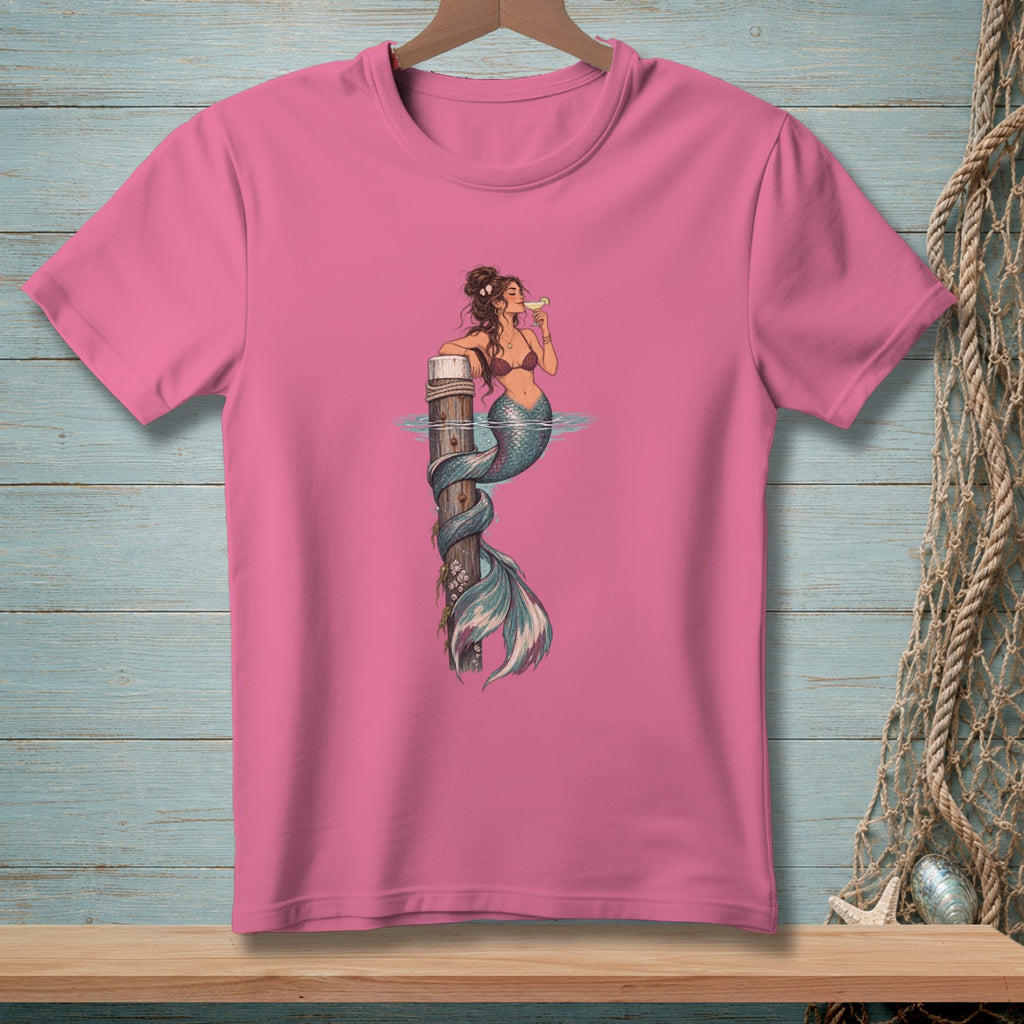 Pink t-shirt with illustration of a mermaid wrapped around a wooden post, drinking from a glass.