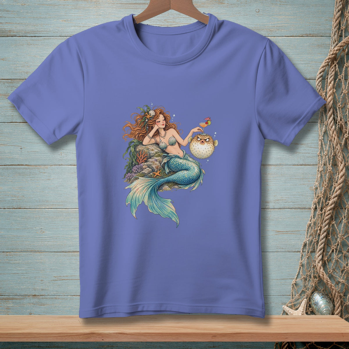Mermaid with red hair and fish tail sits on rocks with a pufferfish and drink.