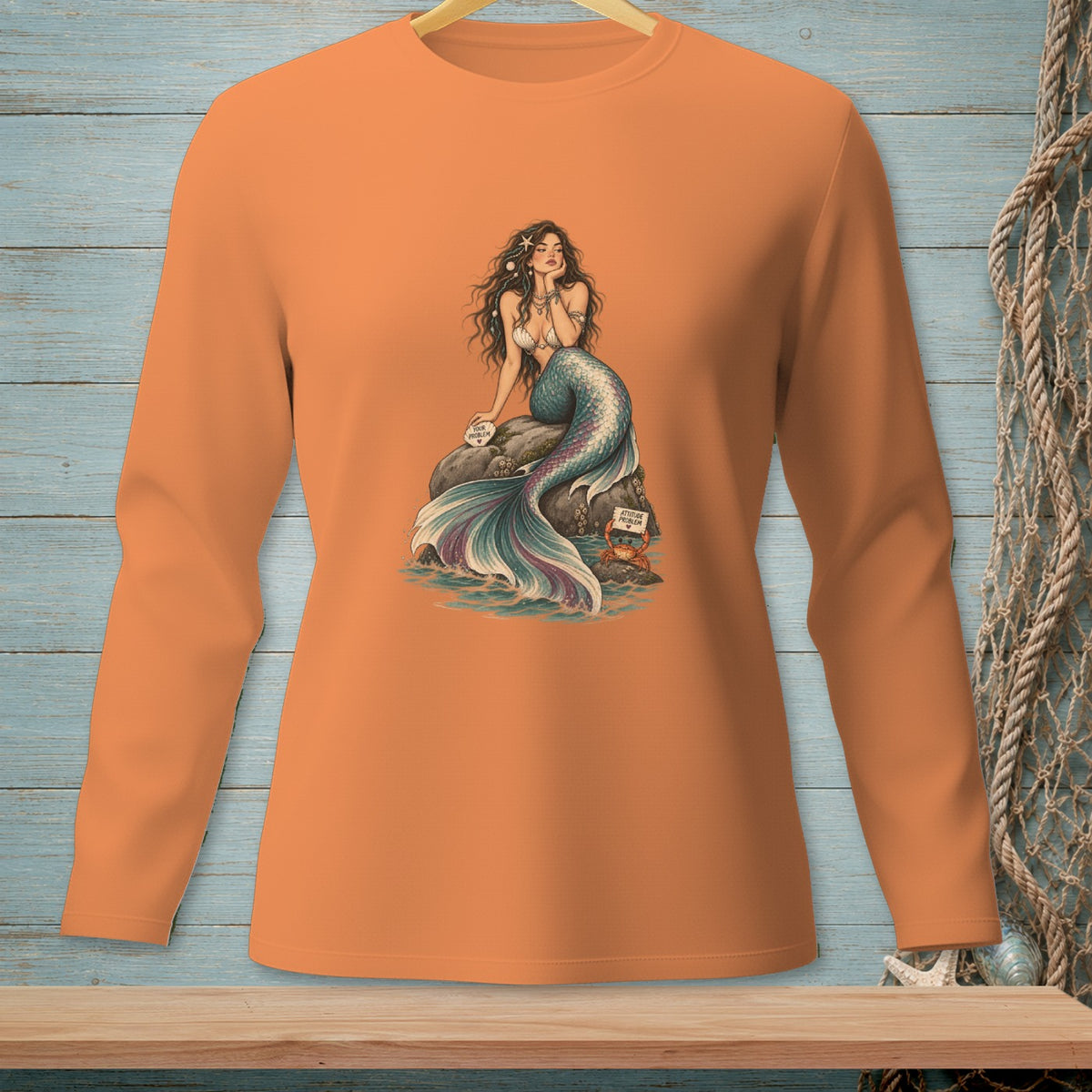 Orange long-sleeve shirt with mermaid graphic and text on rock and crab.