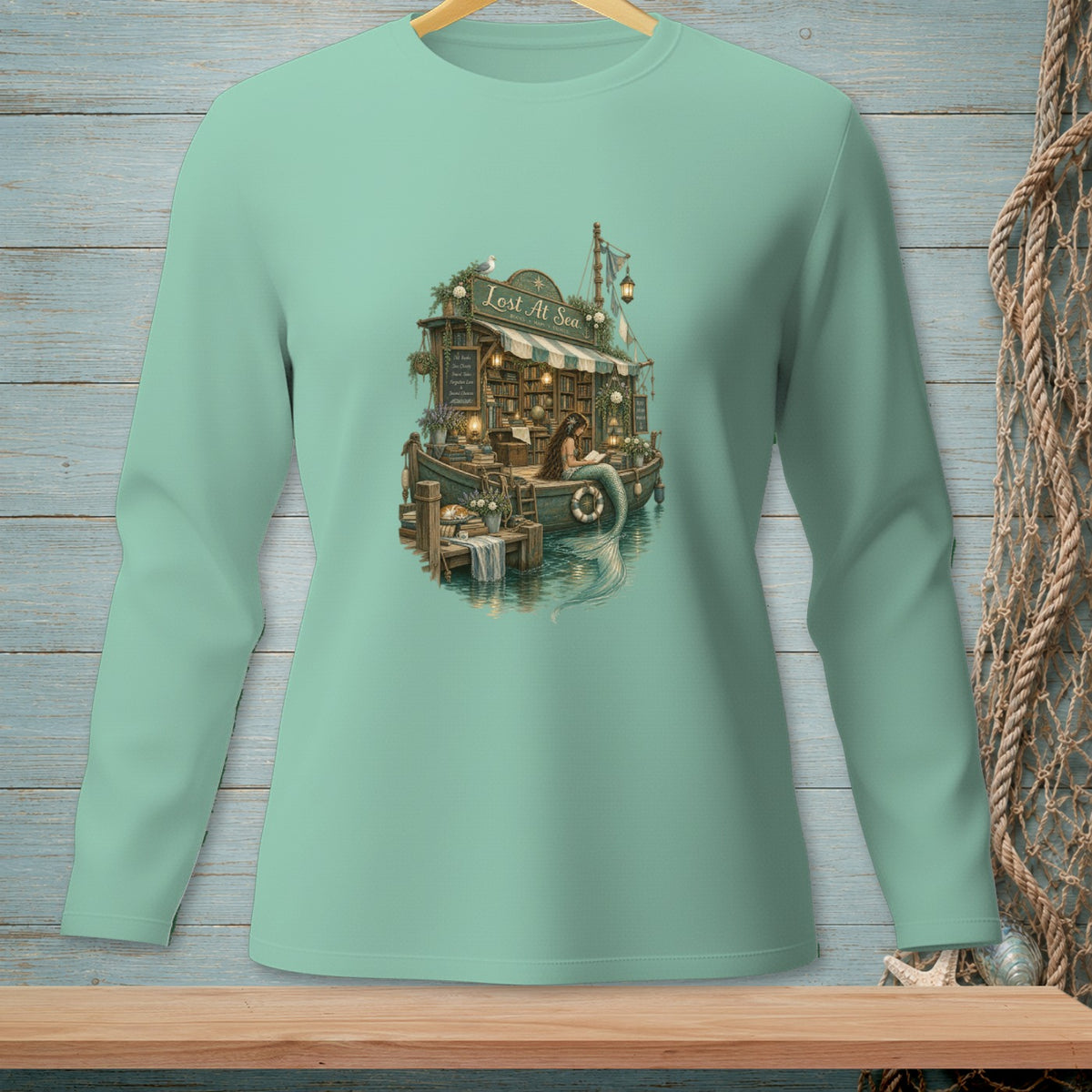 Mint long sleeve shirt with "Lost At Sea" design featuring a mermaid and bookstore on a boat.