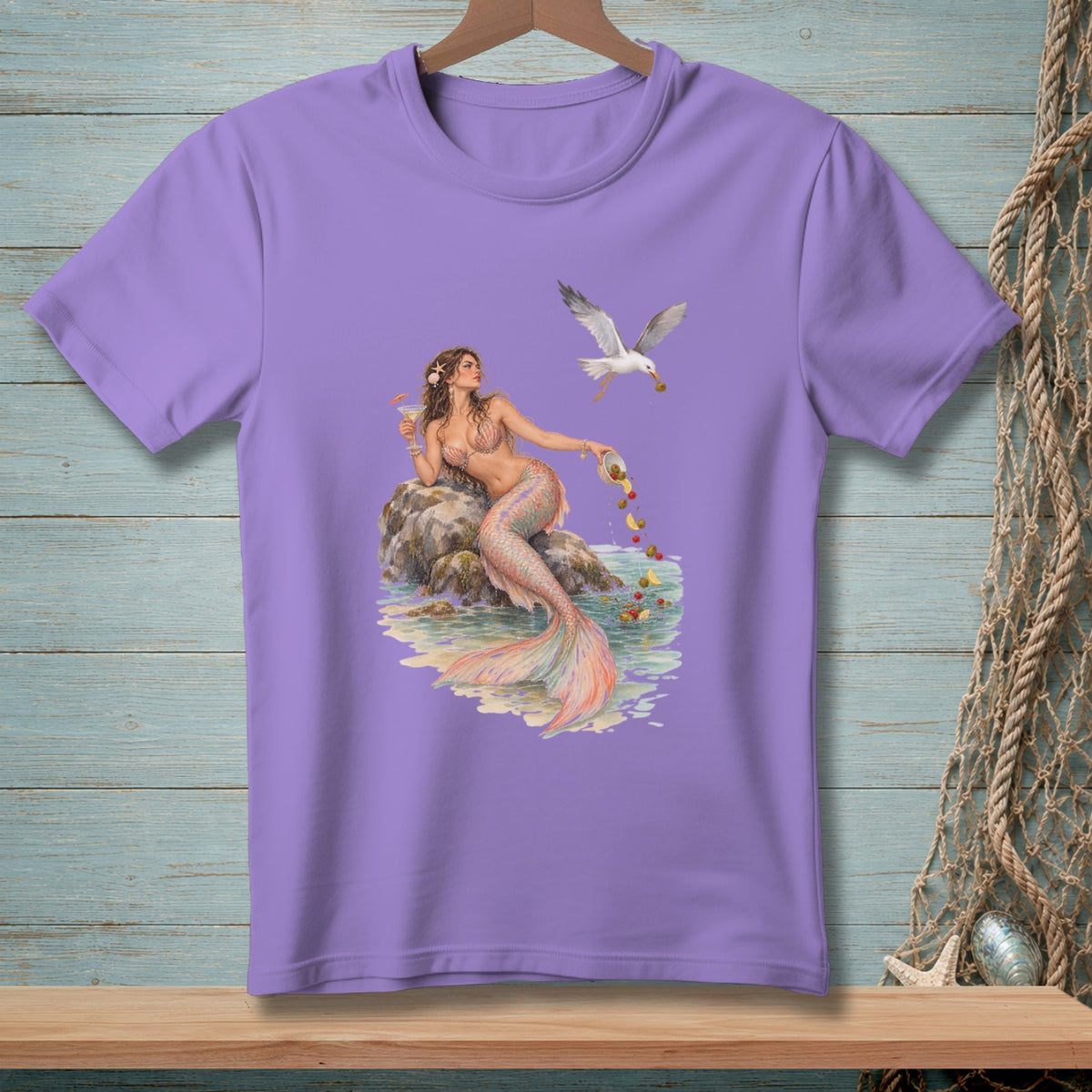 Purple t-shirt with a mermaid sitting on rocks, holding a drink and a bowl of fruit.