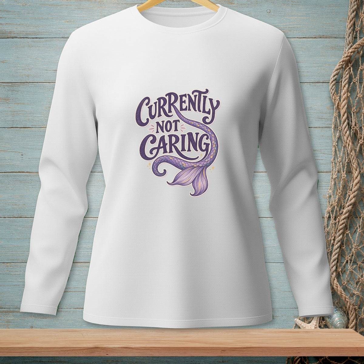 White long-sleeved shirt with "Currently Not Caring" and mermaid tail graphic.