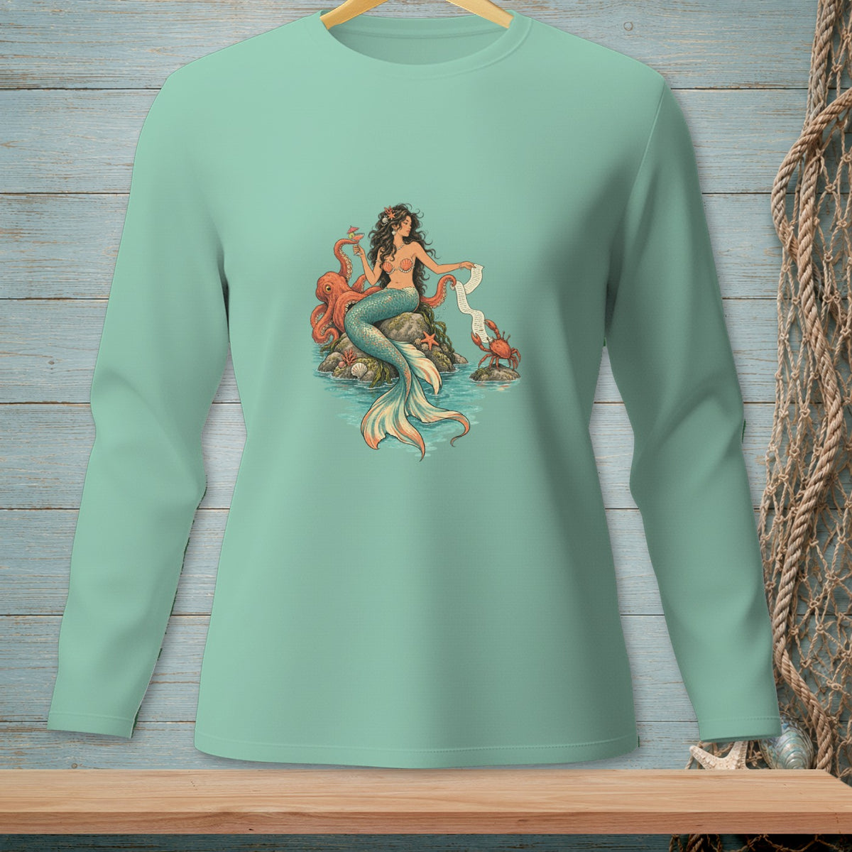 Mermaid with octopus and crab on rocks, seated on a light green long-sleeve shirt.