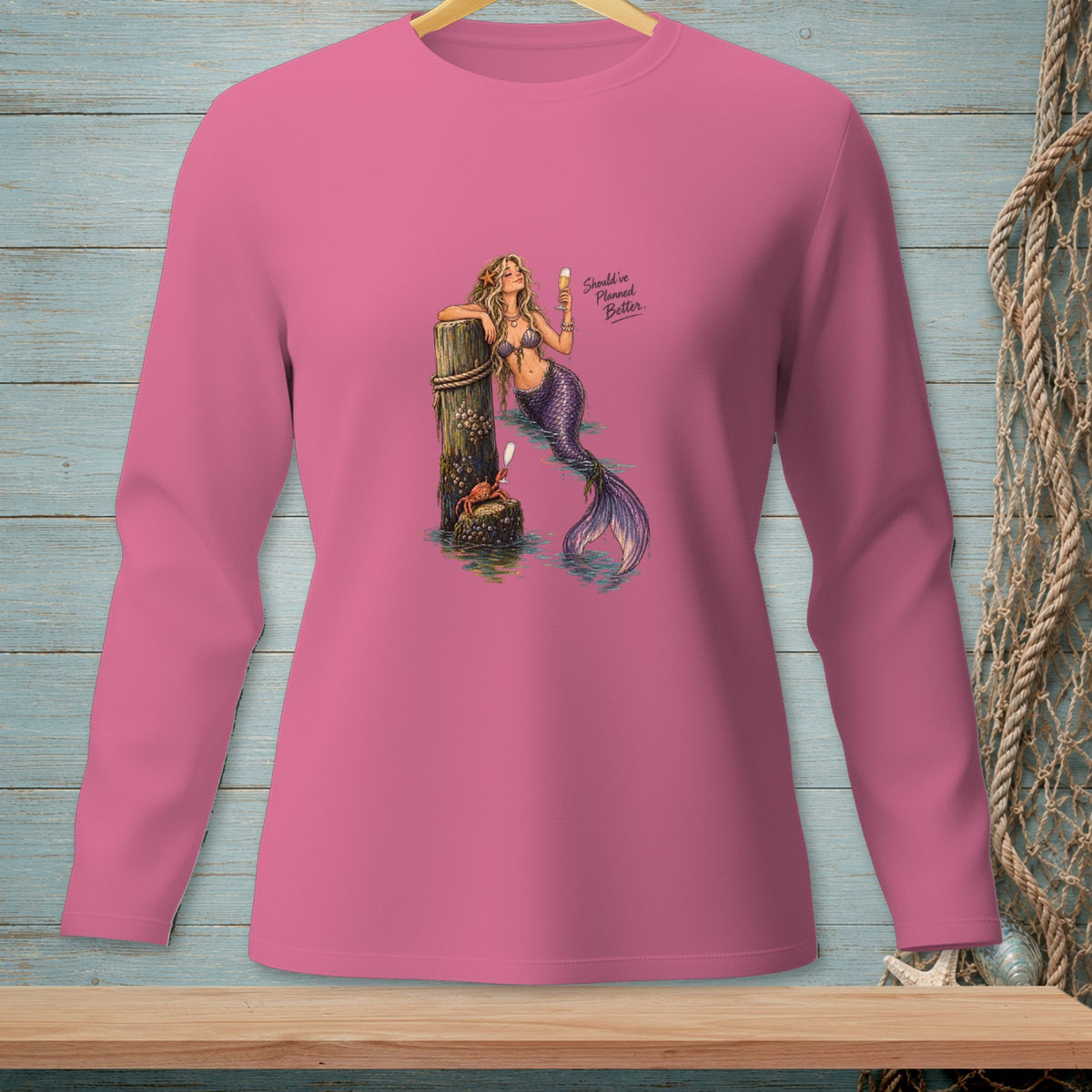 Pink long-sleeve shirt with a mermaid leaning on a post and text.