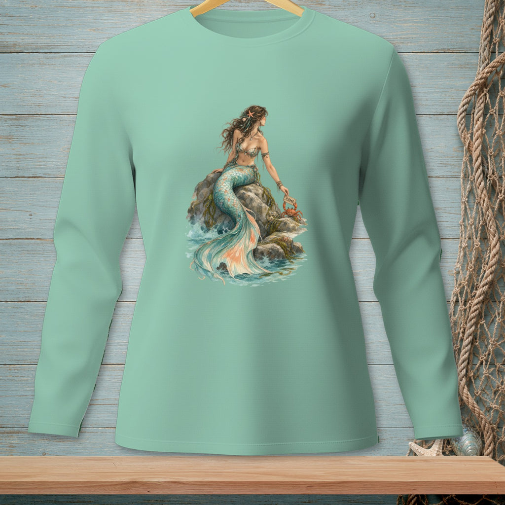 Mermaid sitting on a rock with a crab holding a sign on a mint green long sleeve shirt.