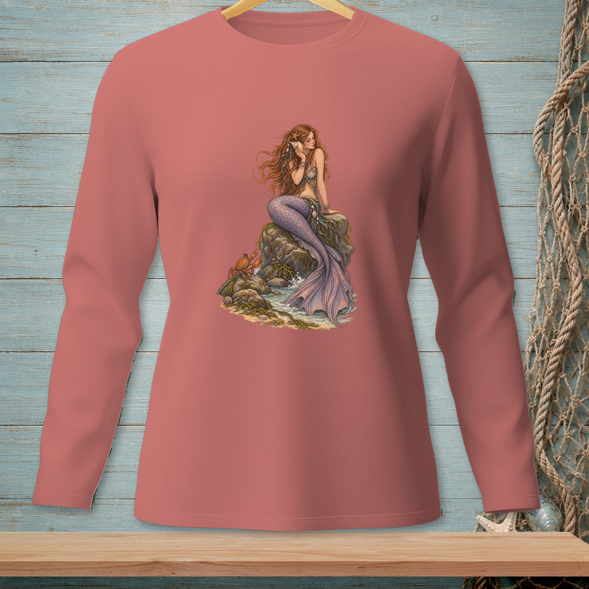 Pink long-sleeve shirt with a detailed mermaid illustration on a rock.