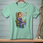 Mint t-shirt with a mermaid sitting on a dock with a seagull and "Thoughts and Prayers" sign.
