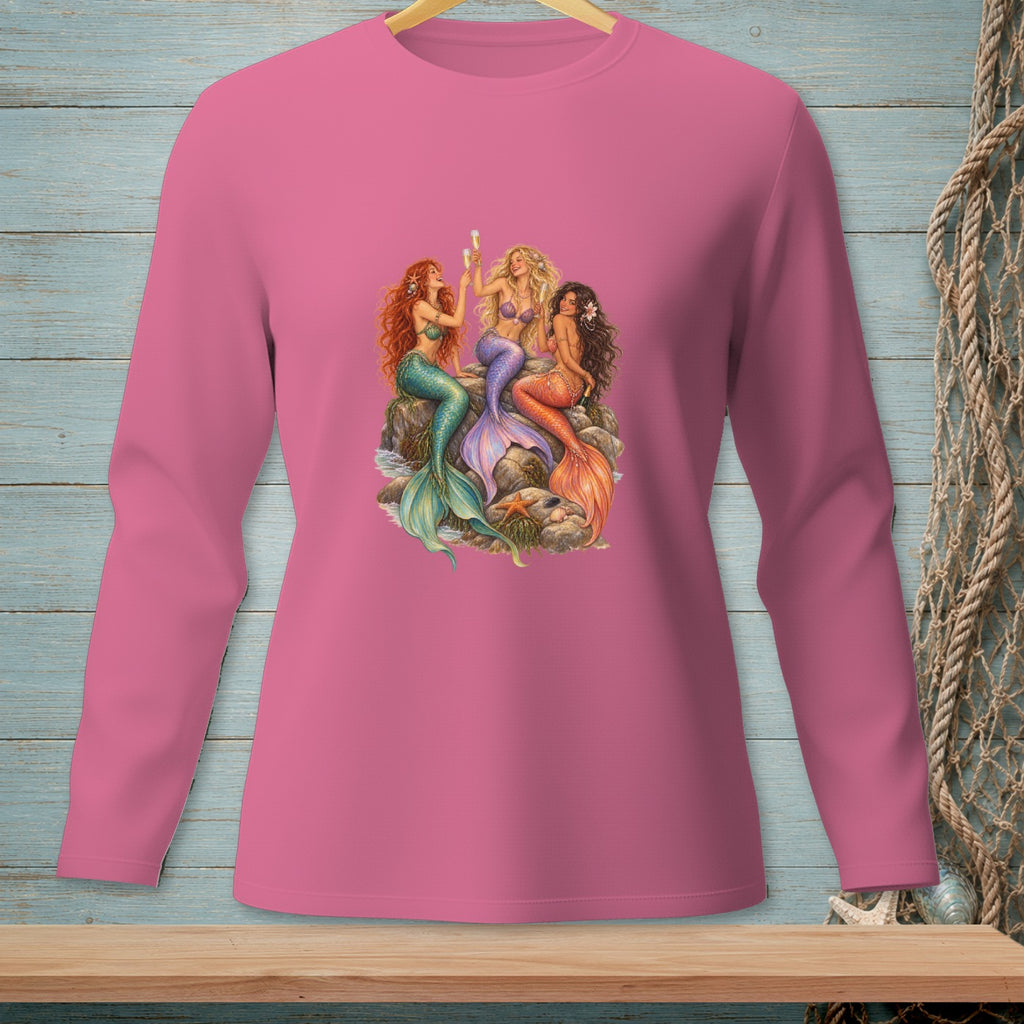 Three mermaids with tails sit on rocks, holding champagne flutes.