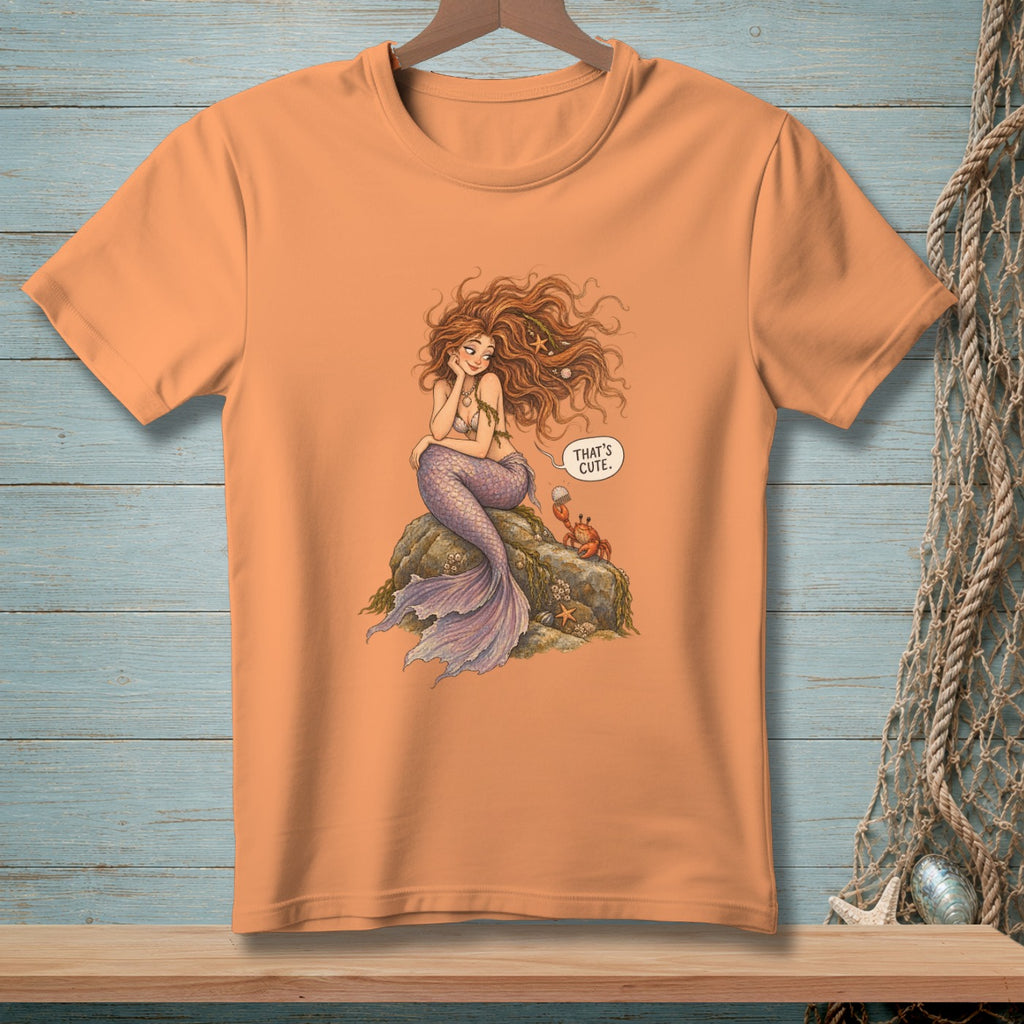 Orange t-shirt with illustration of a mermaid, crab, and speech bubble saying "That's cute."