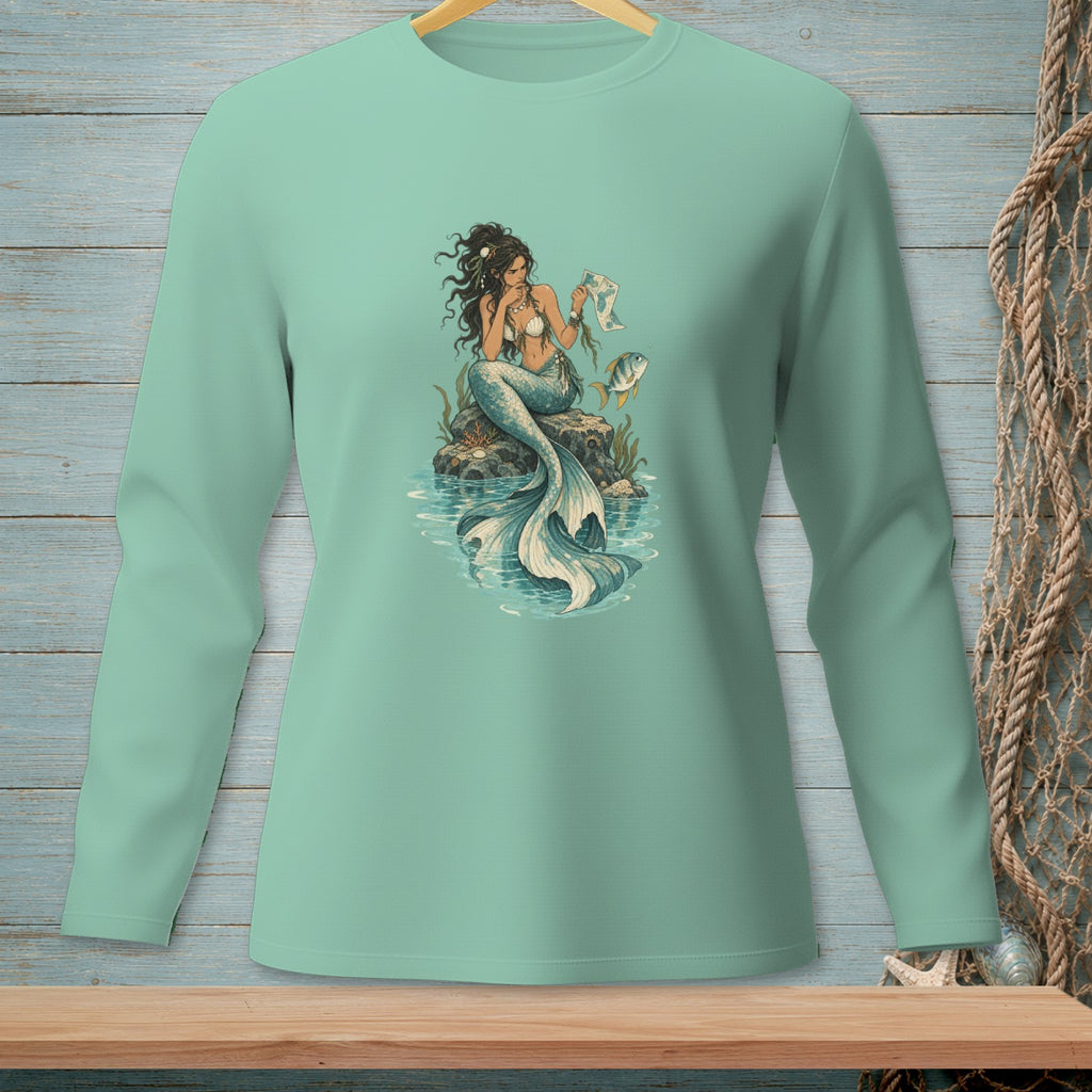 Mint long-sleeve shirt featuring a mermaid sitting on rocks with a fish.