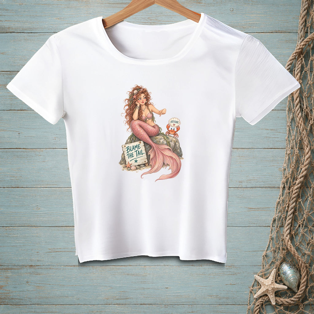 White t-shirt with a mermaid sitting on a rock with a crab and a sign reading "BLAME THE TAIL."