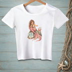 White t-shirt with a mermaid sitting on a rock with a crab and a sign reading "BLAME THE TAIL."