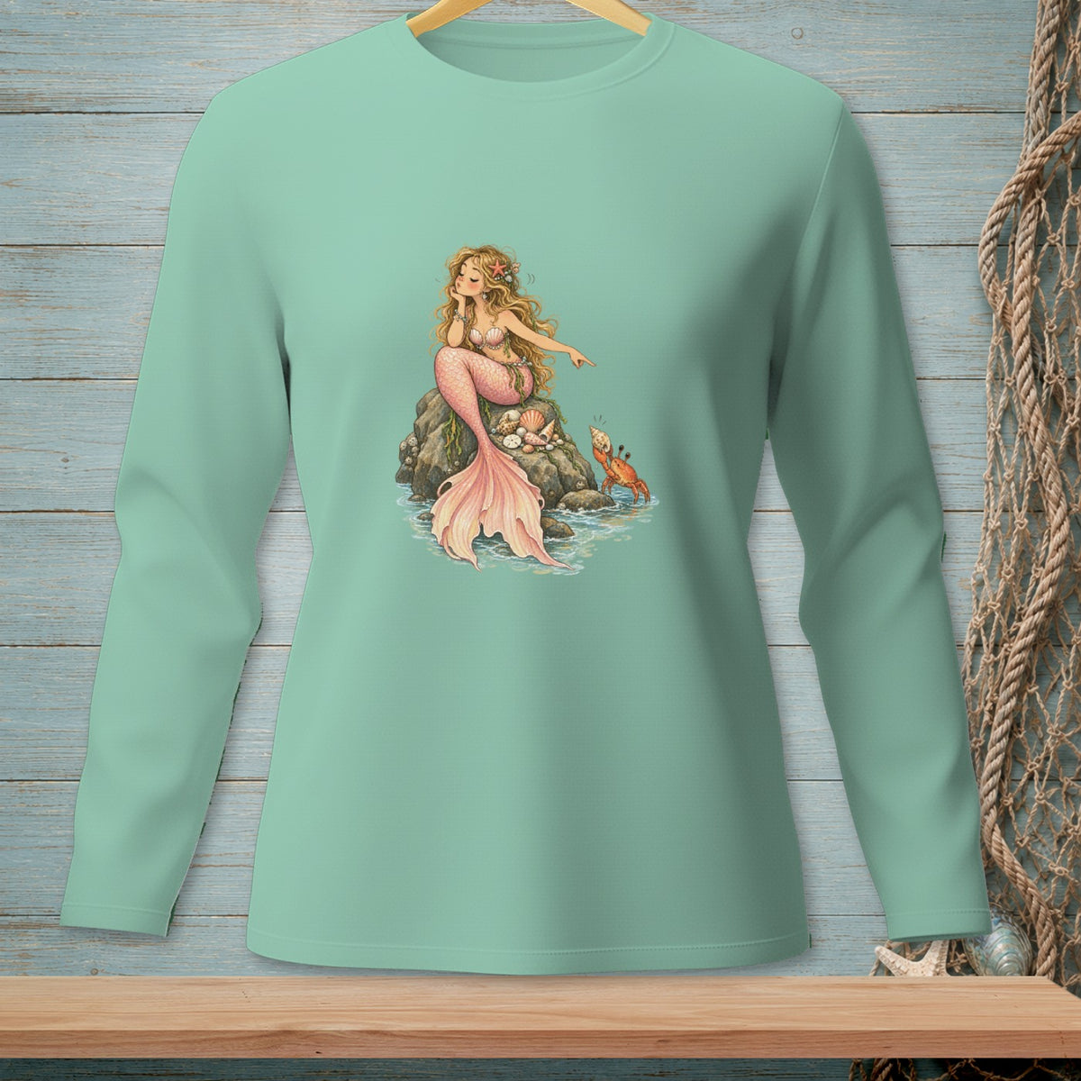 Illustration of a blonde mermaid with a pink tail sitting on a rock with shells and a crab.
