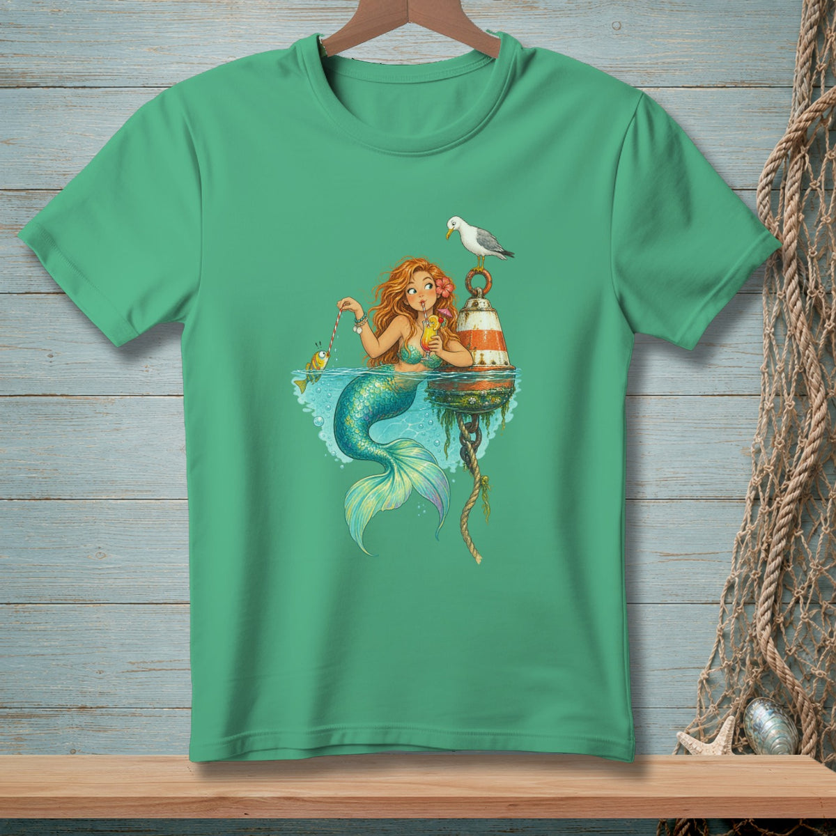 Green t-shirt with a mermaid drinking a cocktail and fishing for a small fish.