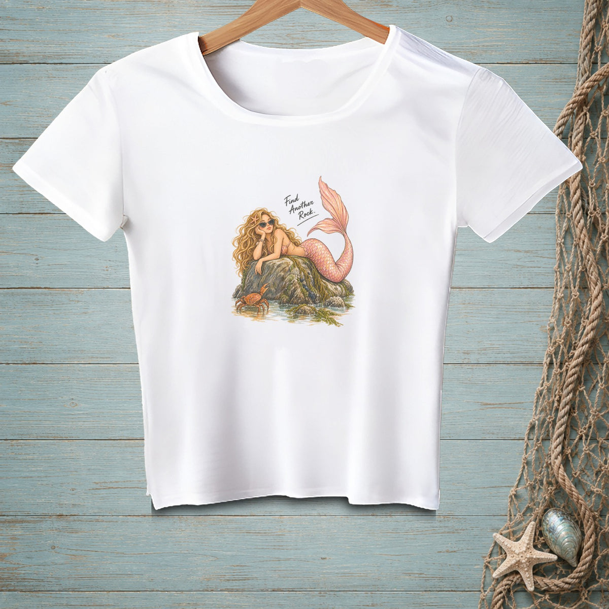 White t-shirt with illustration of a mermaid lounging on a rock with a crab.